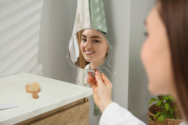 Beautiful woman looking in mirror in bathroom - Photo, Image
