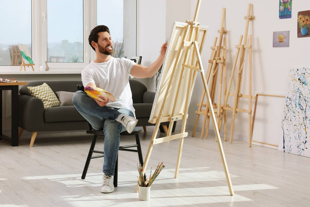 Der Mensch malt im Atelier. Mit Staffelei Leinwand halten - Foto, Bild
