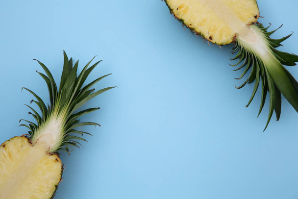 Halves of ripe pineapple on light blue background, flat lay. Space for text - Foto, afbeelding