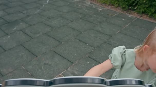 Little cute girl w zielonej sukience letniej z łukiem na placu zabaw gry sam śmiejąc się uśmiechnięte dziecko z dzieciństwa bez nadzoru dorosłych - Materiał filmowy, wideo
