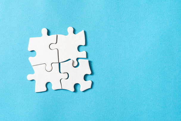 Four pieces of plain white jigsaw puzzle isolated on blue background for business conceptual. - Foto, Imagem