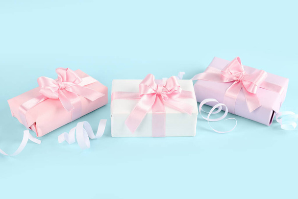 Gift boxes with beautiful bows and serpentine on blue background - Photo, Image