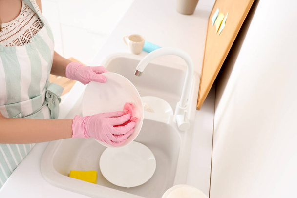 Woman washing plate with sponge in kitchen, closeup - Foto, afbeelding