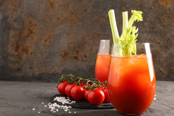 Glasses of bloody mary with celery and tomatoes on grey table - Photo, Image