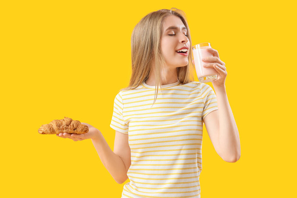 Jovem com croissant saboroso e iogurte no fundo amarelo - Foto, Imagem