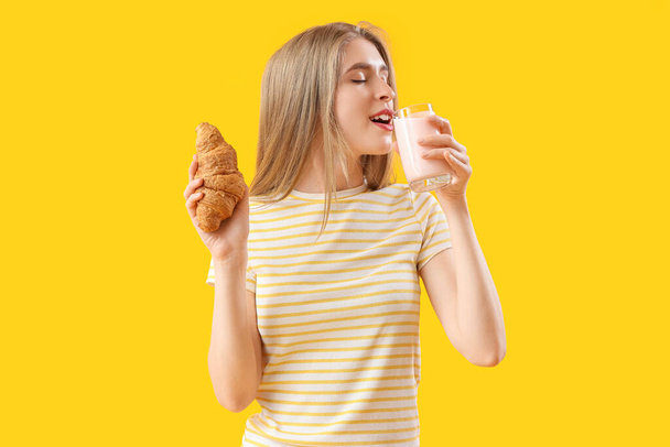 fiatal nő ízletes croissant és joghurt sárga alapon - Fotó, kép