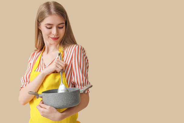 Giovane donna con pentola da cucina su sfondo beige - Foto, immagini