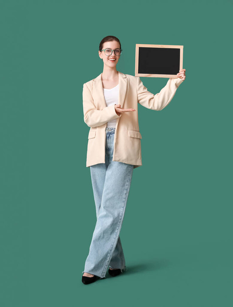 Female teacher with chalkboard on green background - Photo, image
