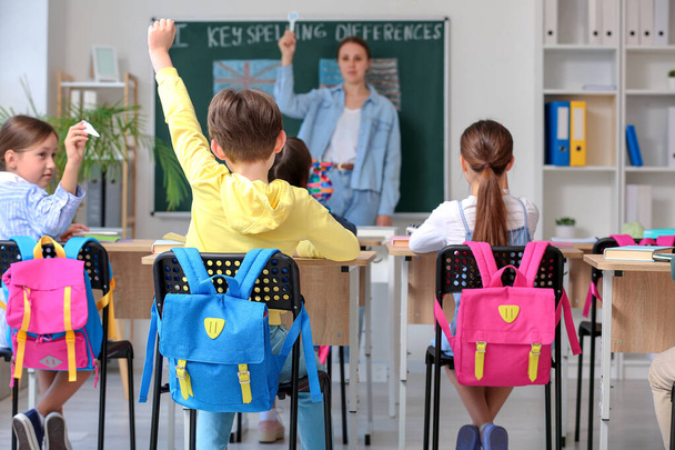 Little pupils with backpacks having lesson in classroom, back view - Φωτογραφία, εικόνα