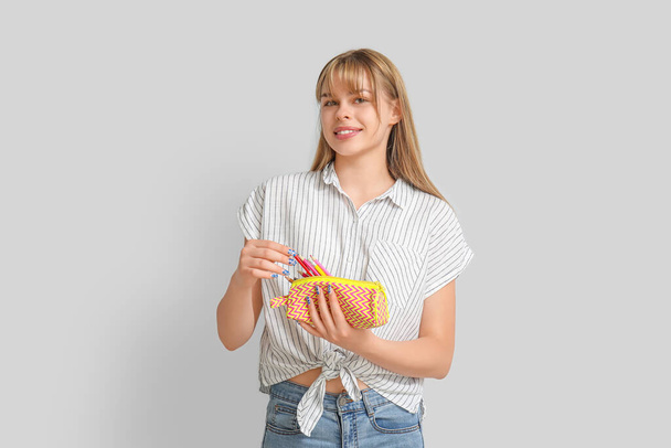 Female student with pencil case on light background - Photo, Image