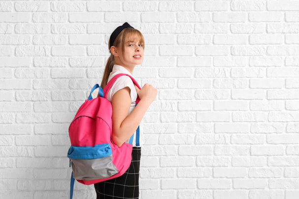 Female student with backpack on white brick background - Foto, imagen