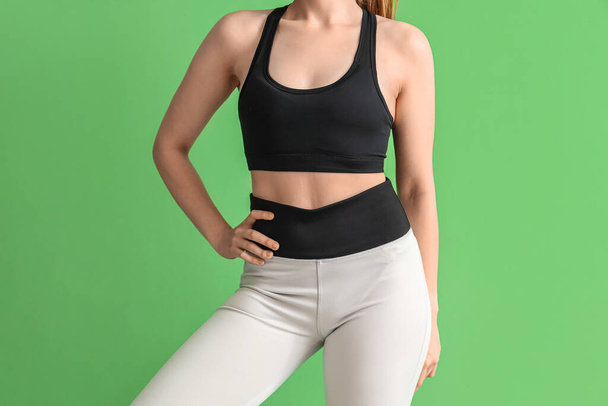 Young woman in sportswear on green background - Photo, Image