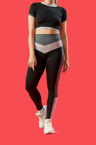 Mujer joven en ropa deportiva sobre fondo rojo - Foto, Imagen