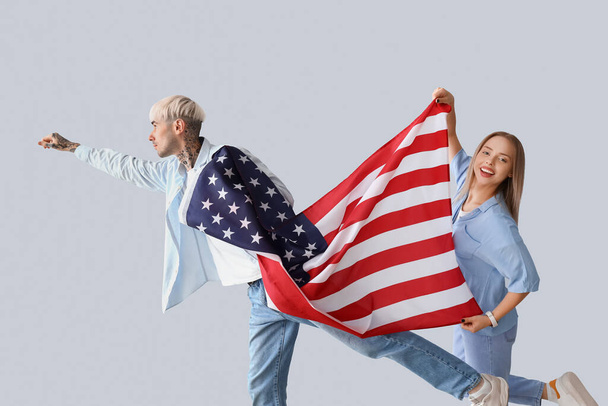 Young couple with USA flag on light background - Foto, imagen