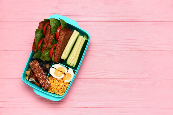 Lunchbox with tasty food on pink wooden background - Valokuva, kuva