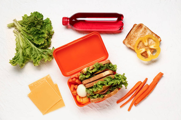Fles sap, groenten en lunchbox met lekker eten op witte achtergrond - Foto, afbeelding