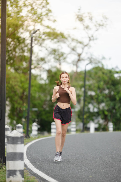 Mulher asiática saudável está correndo ao ar livre. Menina do esporte correndo. Exercício feminino no parque ao ar livre. Pôr do sol ou nascer do sol. Foto de alta qualidade - Foto, Imagem