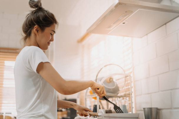 Asian woman in white t-shirt cooking in the kitchen making lunch. - Photo, image