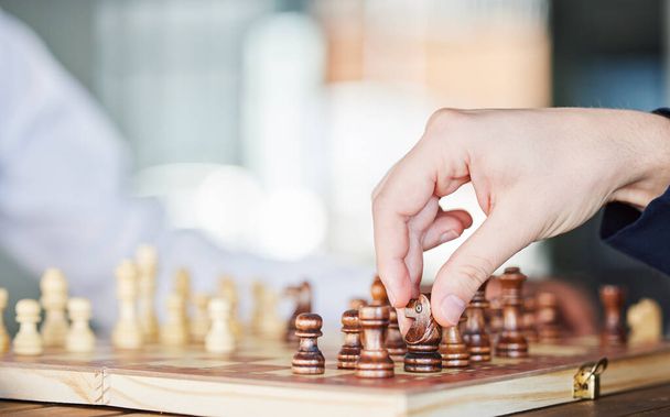 Σκάκι, επιτραπέζιο παιχνίδι και το χέρι ενός άνδρα που παίζει σε ένα τραπέζι, ενώ κινείται κομμάτι για τη στρατηγική ή ματ. Πρόσωπο με ξύλινη εικόνα για να παίξει, να χαλαρώσει και να δέσει ή να λύσει προβλήματα και να αγωνιστεί στον ανταγωνισμό. - Φωτογραφία, εικόνα