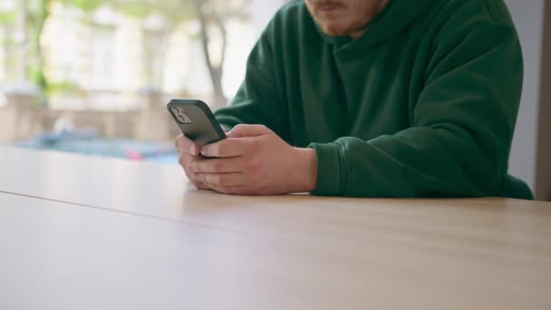 un huésped en la recepción del hotel está sosteniendo un teléfono en sus manos, mensajes de texto con alguien a la espera de check-in el concepto de hospitalidad y tecnología - Metraje, vídeo