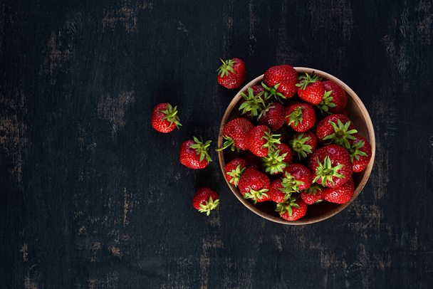 Rote reife Erdbeere auf dunklem Hintergrund. Frische Erdbeeren in Schüssel - Foto, Bild