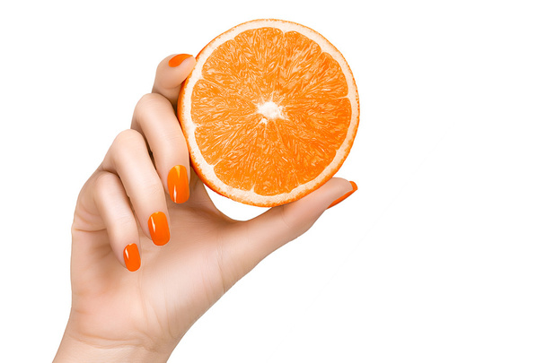 Χέρι με πορτοκαλί καρφιά που κρατούν μια πορτοκαλί φρούτα - Φωτογραφία, εικόνα