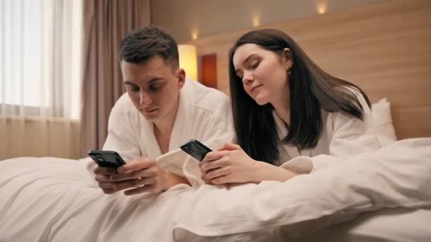 jovem casal no quarto de um quarto de hotel de luxo as pessoas têm smartphones em suas mãos não se comunicar uns com os outros viagens - Filmagem, Vídeo