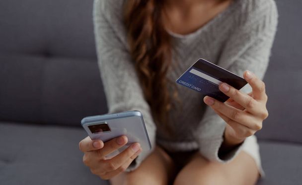 Close up of woman hands holding credit card and smartphone. Young woman paying online using banking entering data shopping order in internet store secure payment. - Photo, Image