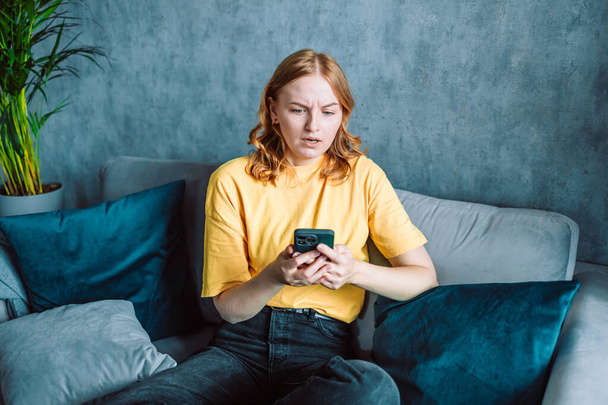 Shocked concerned cellphone user girl staring at screen, looking at smartphone screen, finding problems with online app, poor connection, Internet service, getting surprising bad news. High quality - Φωτογραφία, εικόνα