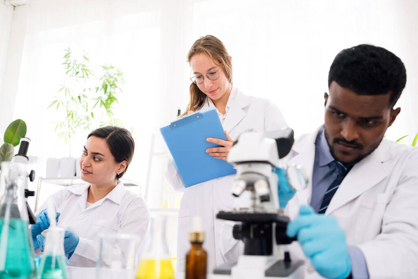 Różnorodność naukowców przekazuje wyniki eksperymentów swoim kolegom w laboratorium badawczym. Grupa studentów chemii pracujących w laboratorium. - Zdjęcie, obraz