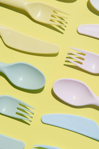 close up pattern of multi-use plastic cutlery on a pastel yellow background - Foto, immagini
