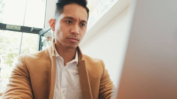 Gros plan, jeune homme d'affaires beau en costume beige travaillant avec un ordinateur portable dans un café - Photo, image