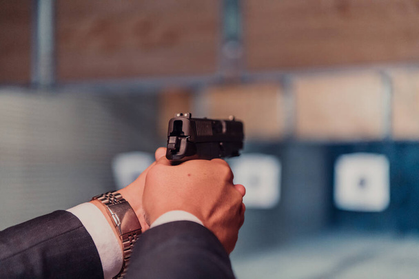 Een man oefent schieten met een pistool in een schietbaan terwijl hij een beschermende hoofdtelefoon draagt.  - Foto, afbeelding
