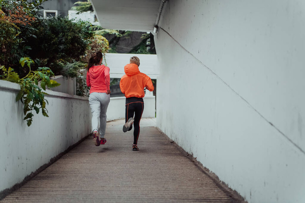 Two women in sports clothes running in a modern urban environment. The concept of a sporty and healthy lifestyle.  - Φωτογραφία, εικόνα