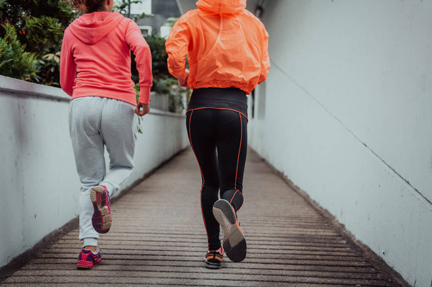 Two women in sports clothes running in a modern urban environment. The concept of a sporty and healthy lifestyle.  - Foto, imagen