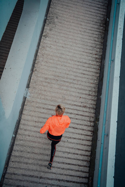 Top view photo of omen in sports clothes running in a modern urban environment. The concept of a sporty and healthy lifestyle.  - Фото, изображение