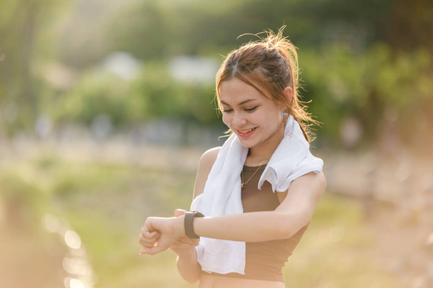 Healthy woman relax after cool down and looking smart watch for check timing run. Woman workout after fitness and jogging session at the park. Healthy and Lifestyle Concept. High quality photo - Foto, Bild