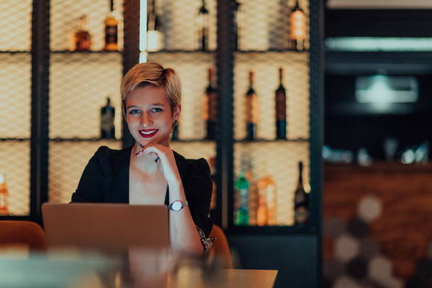 Businesswoman sitting in a cafe while focused on working on a laptop and participating in an online meetings. Selective focus - 写真・画像