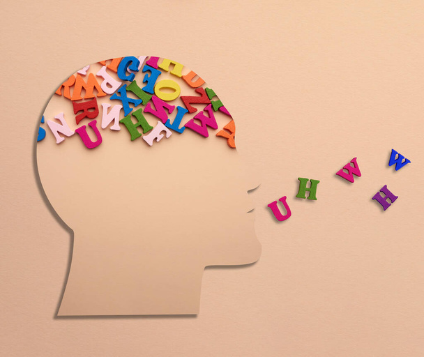 Silhouette di una testa umana con lettere nel cervello su sfondo beige. Concetto di elaborazione delle informazioni, analisi dei dati - Foto, immagini