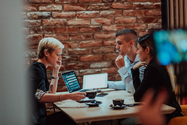 Happy businesspeople smiling cheerfully during a meeting in a coffee shop. Group of successful business professionals working as a team in a multicultural workplace.  - 写真・画像