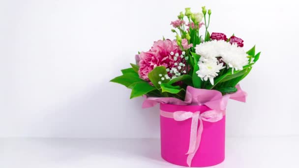 Velká krásná kytice různých přírodních květin v růžové dárkové krabičce. Bílé pozadí. Pozdrav k narozeninám, ke dni matek, ke dni žen nebo k jiné příležitosti. Zastavit animaci pohybu. Kopírovat prostor. - Záběry, video