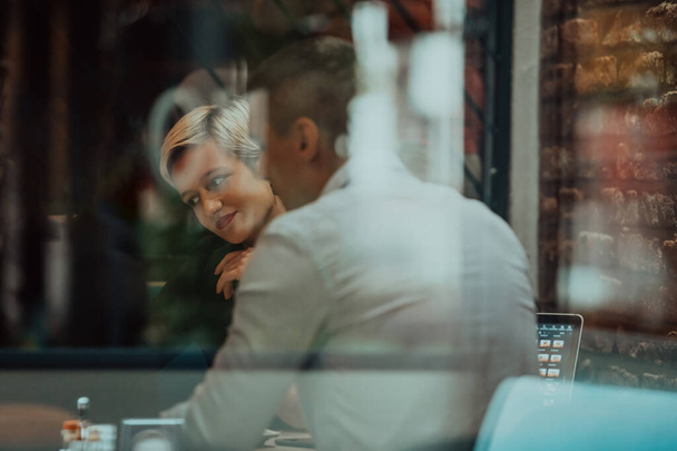 Feliz gente de negocios sonriendo alegremente durante una reunión en una cafetería. Grupo de profesionales de negocios exitosos trabajando en equipo en un lugar de trabajo multicultural.  - Foto, imagen