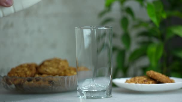 Le lait est versé dans un verre, le matin le lait de petit déjeuner avec des biscuits à l'avoine. au ralenti - Séquence, vidéo