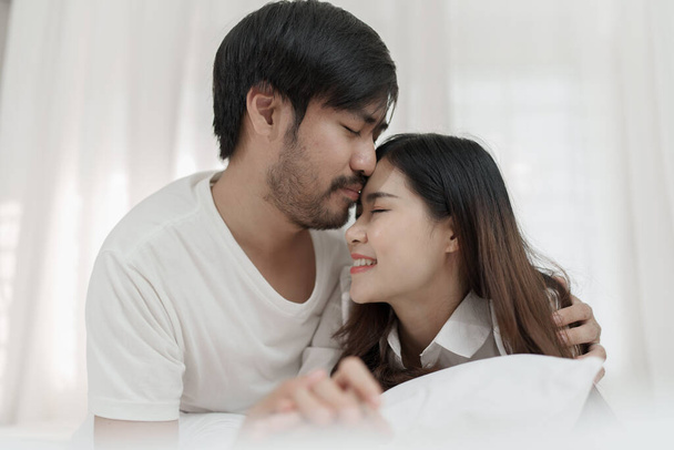 官能的な前戯を楽しむベッドでアジアのロマンチックなカップル一緒にベッドに横たわって幸せな官能的な若いカップル。美しいです愛カップルキスでベッド - 写真・画像