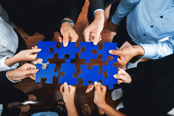 Von oben betrachtet halten multiethnische Geschäftsleute Puzzleteile und verschmelzen sie als effektive Lösung zur Lösung von Teamarbeit, gemeinsamer Vision und gemeinsamem Ziel, das unterschiedliche Talente vereint. Akribisch - Foto, Bild