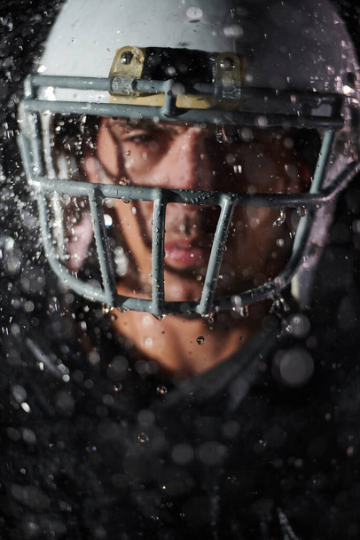 American Football Field: Lonely Athlete Warrior Standing on a Field Holds his Helmet and Ready to Play. Player Preparing to Run, Attack and Score Touchdown. Rainy Night with Dramatic Fog, Blue Light. - Foto, imagen