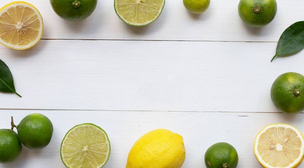 Rijpe citroenen en limoenen op witte houten achtergrond. - Foto, afbeelding