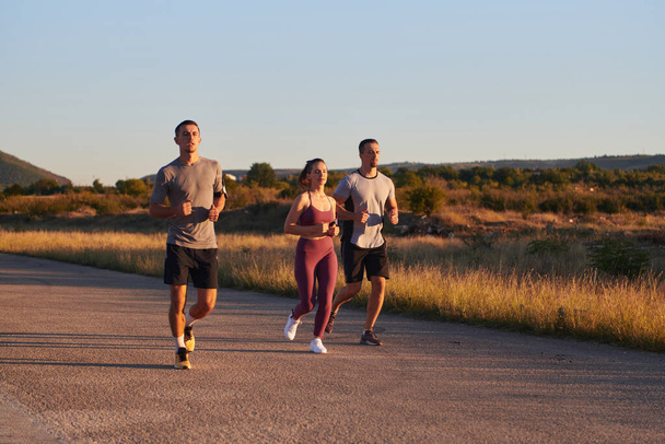 Um grupo de jovens atletas correndo juntos no início da manhã luz do nascer do sol, mostrando sua energia coletiva, determinação e unidade . - Foto, Imagem