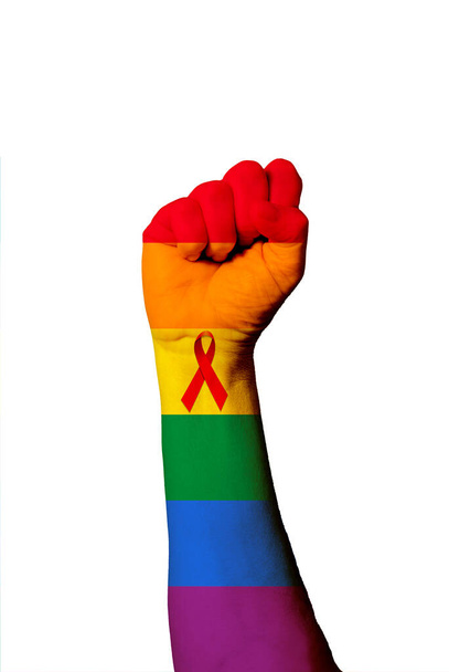 Вертикальный снимок радужного флага гей-прайда с лентой Всемирного дня помощи, нарисованной на человеческом поднятом кулаке - Фото, изображение