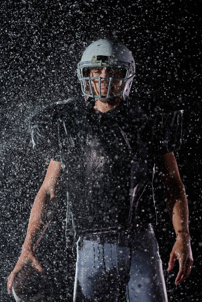American Football Field: Lonely Athlete Warrior Standing on a Field Holds his Helmet and Ready to Play. Player Preparing to Run, Attack and Score Touchdown. Rainy Night with Dramatic Fog, Blue Light. - Foto, immagini